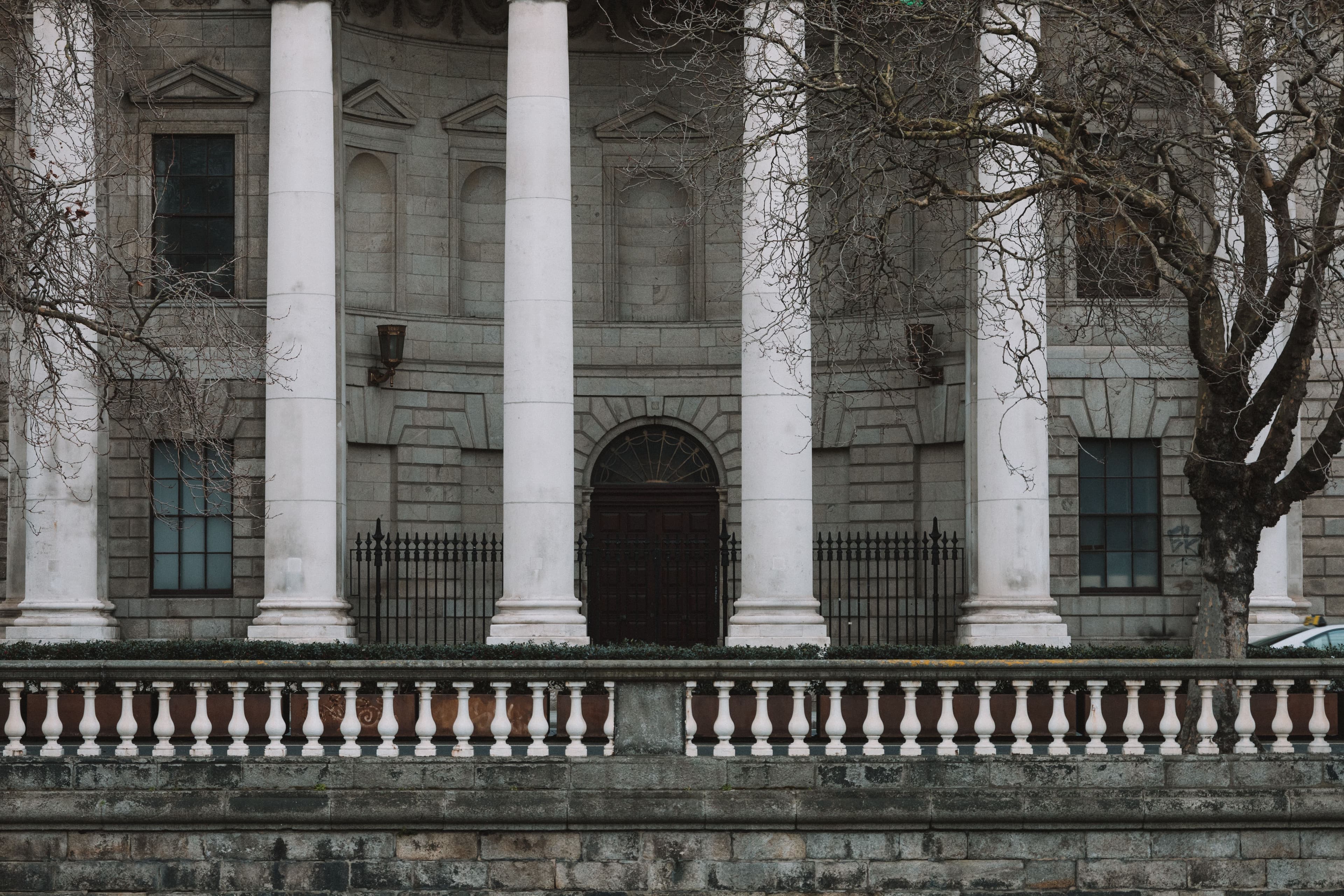 The curved stone façade of a classical bank building with tall columns and iron railings, seen from the street.